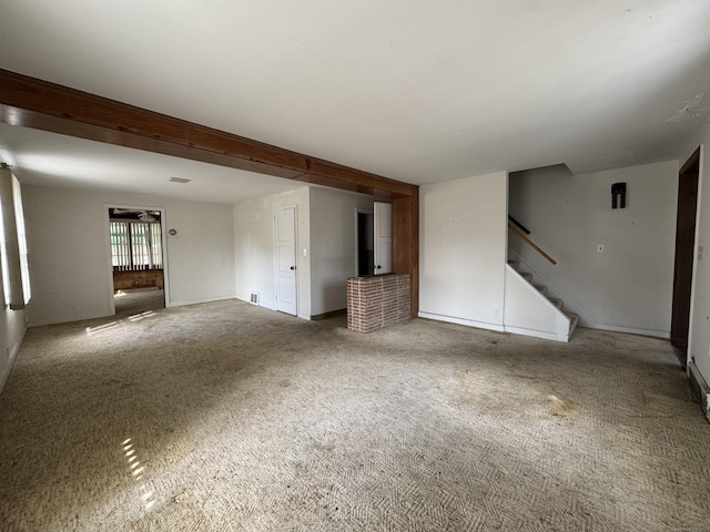 carpeted spare room with visible vents and stairs