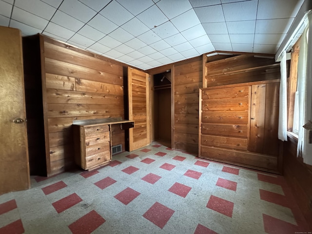 interior space with lofted ceiling, visible vents, and wooden walls