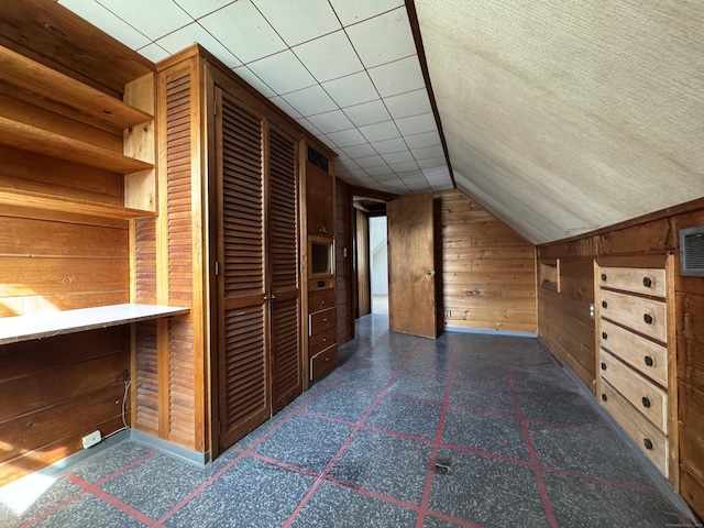 bonus room featuring wood walls, dark floors, and vaulted ceiling