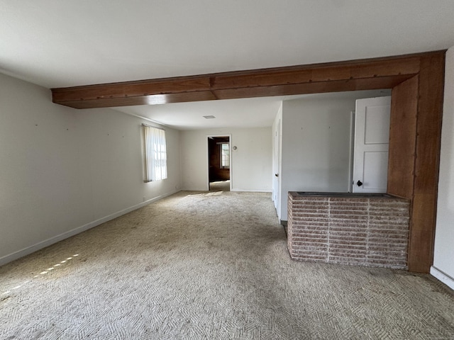 spare room with light carpet, baseboards, and beamed ceiling