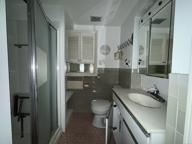 bathroom featuring a wainscoted wall, tile walls, toilet, a shower stall, and vanity