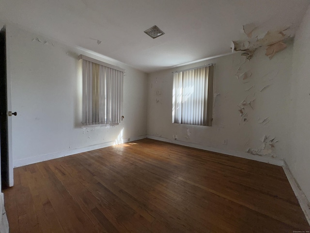 spare room featuring baseboards and dark wood-type flooring