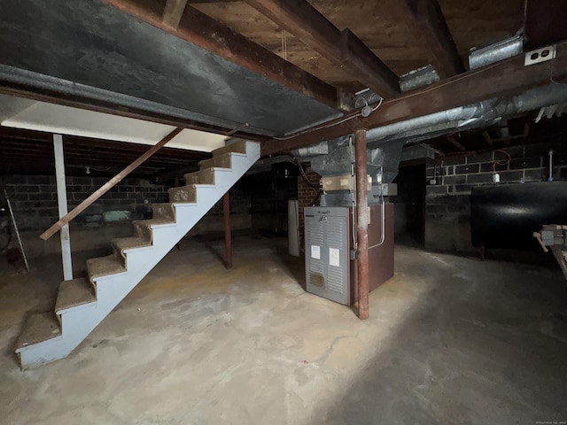 unfinished below grade area with stairway, heating unit, and heating fuel