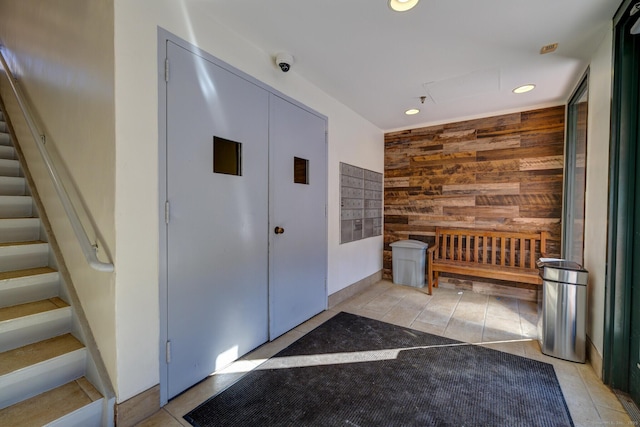 interior space with light tile patterned floors, a mail area, and wood walls