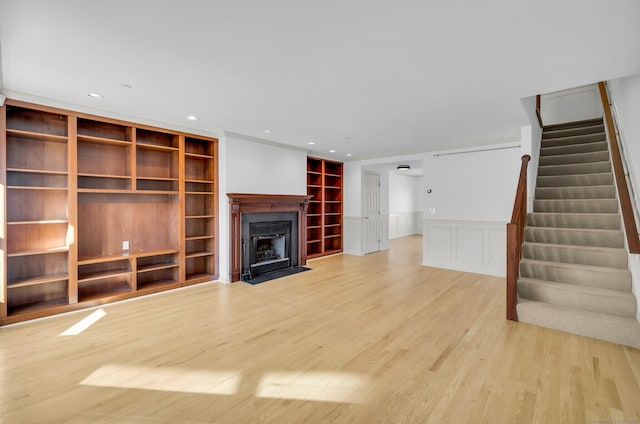 unfurnished living room with built in shelves and light wood-type flooring