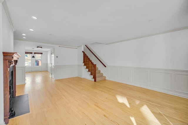 unfurnished living room with ornamental molding and light wood-type flooring