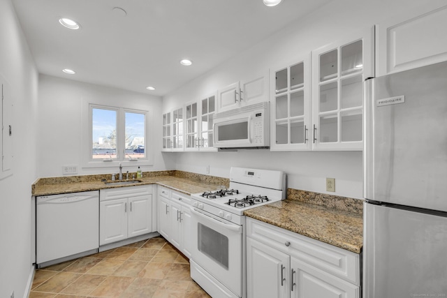 kitchen with white appliances, stone countertops, sink, and white cabinets