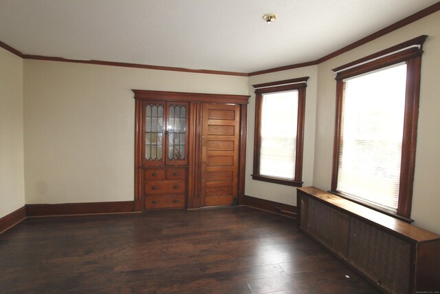 empty room featuring crown molding, radiator, and dark hardwood / wood-style flooring