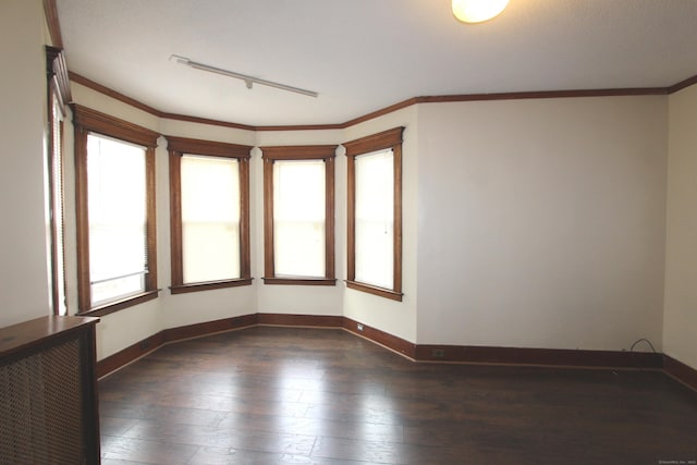 spare room with ornamental molding, dark hardwood / wood-style flooring, and rail lighting