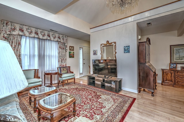 living room featuring light hardwood / wood-style floors, an inviting chandelier, and lofted ceiling