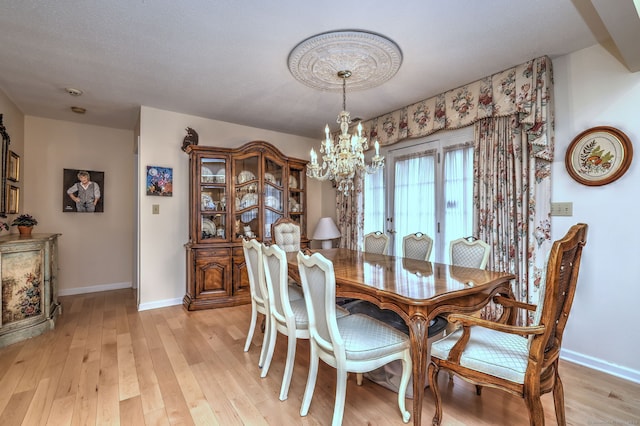 dining room with light wood-type flooring and a chandelier