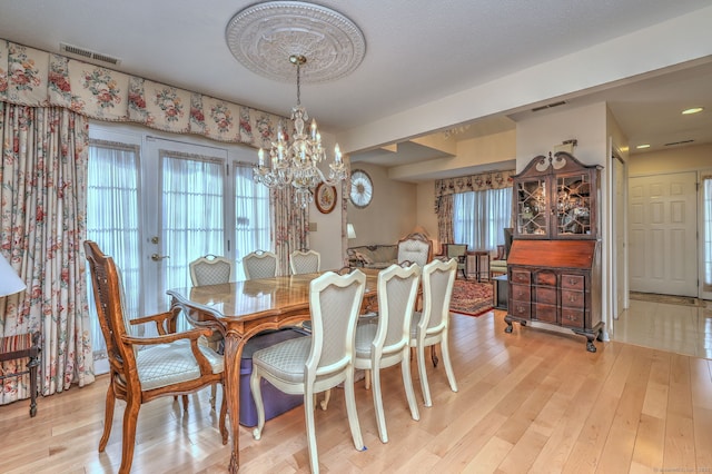 dining space with light hardwood / wood-style floors and a chandelier