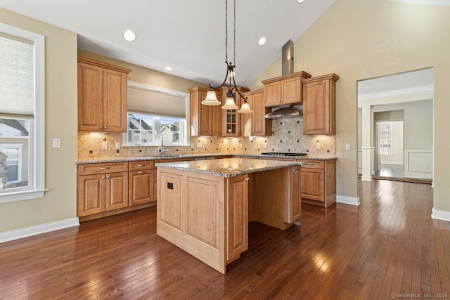 kitchen with light stone countertops, a center island, pendant lighting, and dark hardwood / wood-style flooring