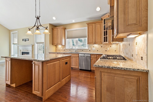 kitchen with pendant lighting, sink, stainless steel appliances, a center island, and light stone counters