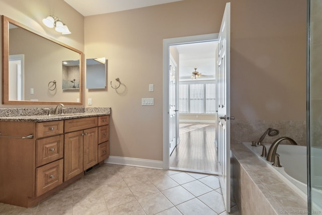 bathroom featuring vanity, a relaxing tiled tub, tile patterned floors, and ceiling fan