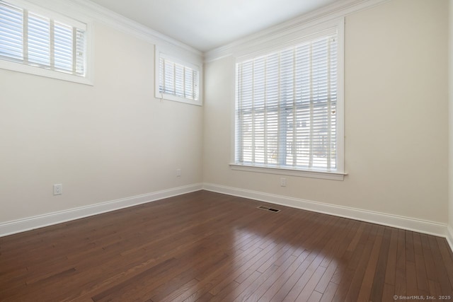 empty room featuring dark wood-type flooring, ornamental molding, and a wealth of natural light