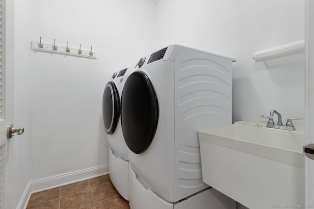 clothes washing area with sink, washer and dryer, and dark tile patterned flooring