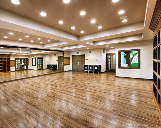 unfurnished living room with hardwood / wood-style flooring and a tray ceiling