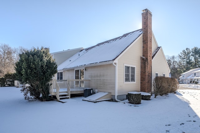 snow covered rear of property featuring a wooden deck and central AC