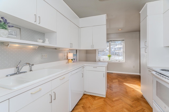 kitchen with sink, white appliances, light parquet floors, white cabinets, and kitchen peninsula