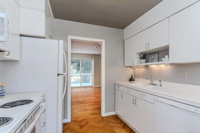 kitchen with sink, white appliances, light parquet floors, and white cabinets