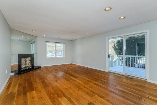 unfurnished living room featuring a tile fireplace and wood-type flooring