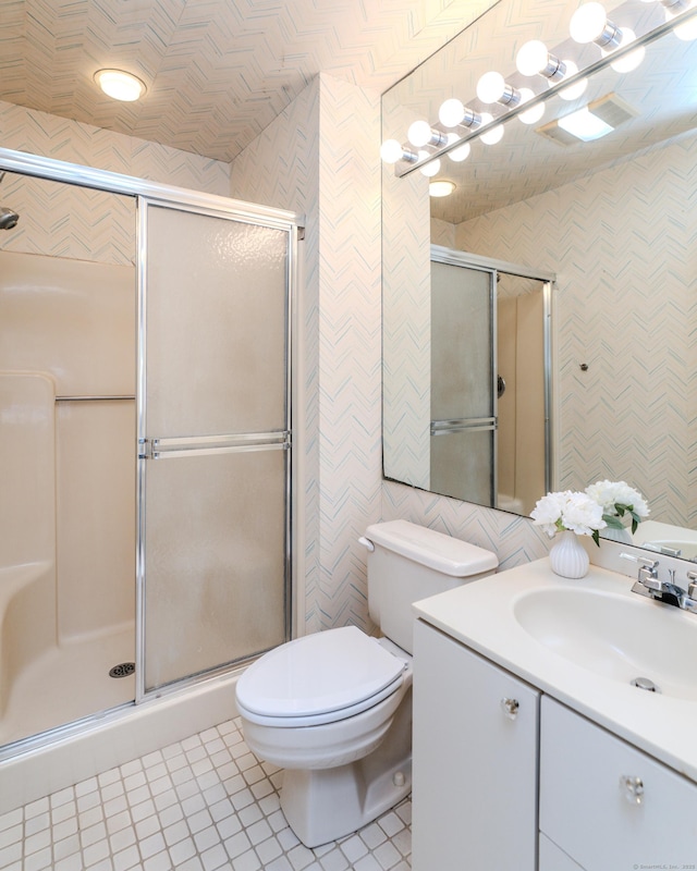 bathroom with a shower with door, tile walls, vanity, tile patterned floors, and toilet