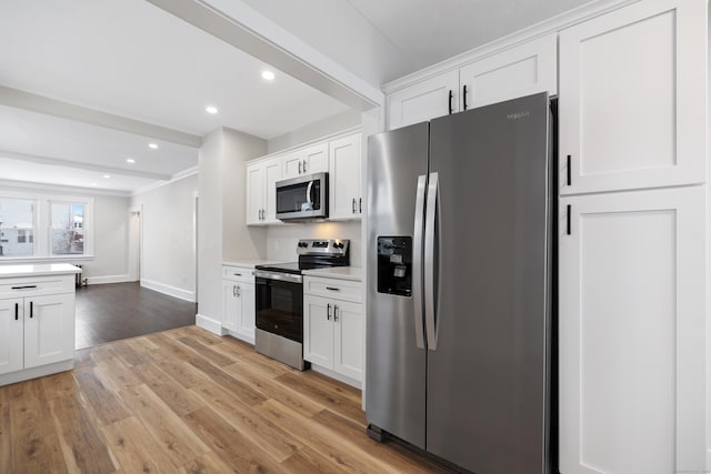 kitchen featuring beam ceiling, light hardwood / wood-style floors, white cabinets, and appliances with stainless steel finishes