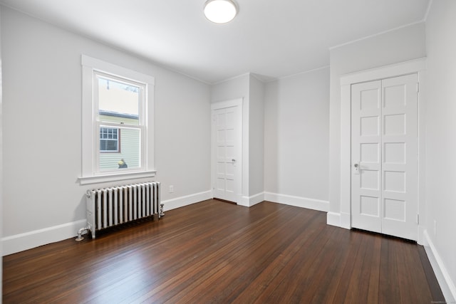 empty room with dark hardwood / wood-style floors and radiator