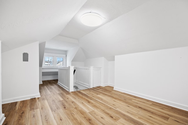 additional living space with vaulted ceiling and light wood-type flooring