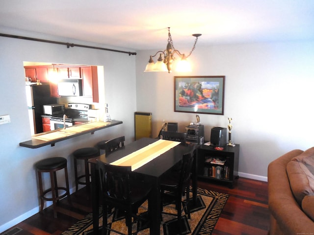 dining area with dark hardwood / wood-style floors and a chandelier