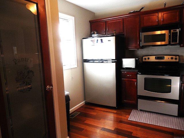 kitchen with appliances with stainless steel finishes and dark wood-type flooring