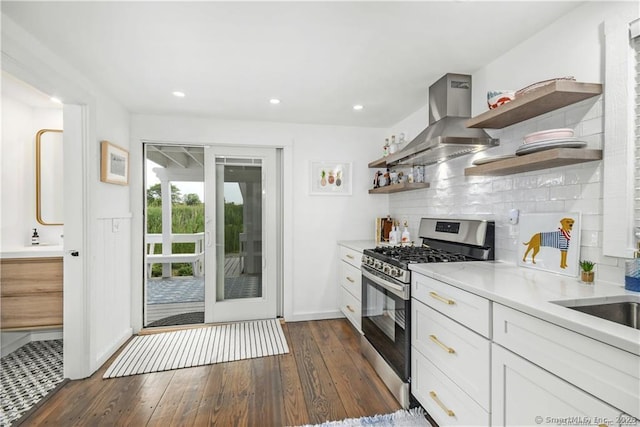 kitchen with white cabinetry, backsplash, stainless steel range with gas stovetop, island range hood, and dark hardwood / wood-style flooring