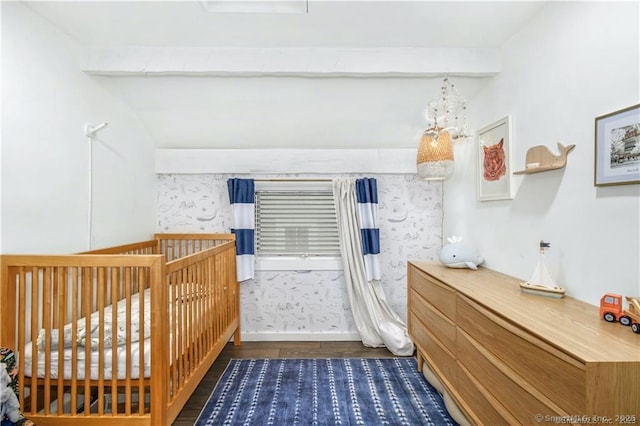 bedroom featuring beamed ceiling, dark hardwood / wood-style flooring, and a crib