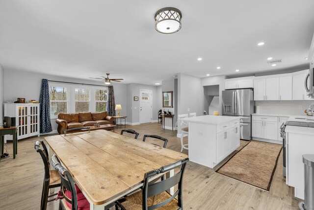 kitchen with white cabinetry, appliances with stainless steel finishes, a kitchen island, light hardwood / wood-style floors, and decorative backsplash