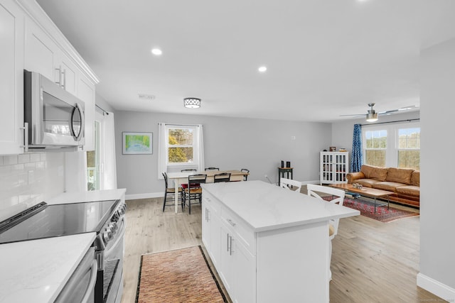 kitchen featuring light hardwood / wood-style flooring, backsplash, stainless steel appliances, a healthy amount of sunlight, and white cabinets