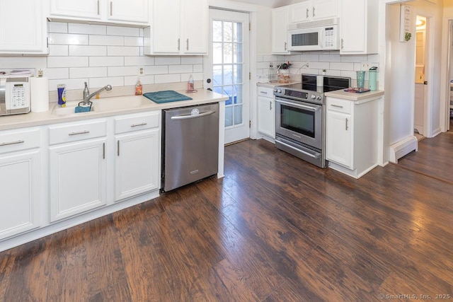 kitchen featuring sink, dark wood-type flooring, appliances with stainless steel finishes, white cabinetry, and decorative backsplash