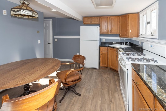 kitchen featuring dark stone countertops, sink, white appliances, and dark wood-type flooring