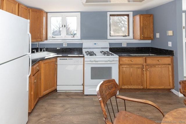 kitchen with dark hardwood / wood-style flooring, sink, white appliances, and dark stone countertops