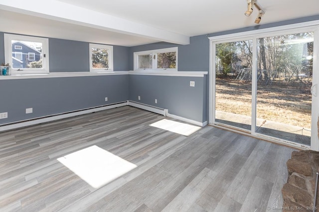 unfurnished room featuring hardwood / wood-style flooring, baseboard heating, and beamed ceiling