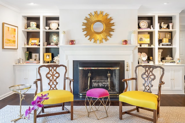 living area with wood-type flooring, ornamental molding, and built in features