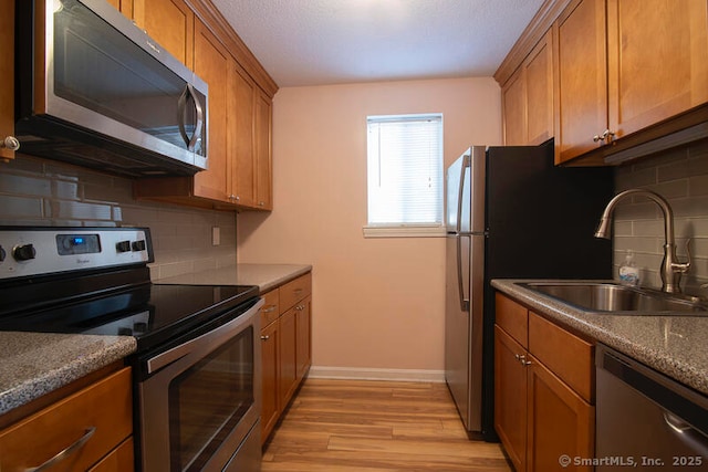 kitchen with sink, decorative backsplash, light hardwood / wood-style flooring, and appliances with stainless steel finishes