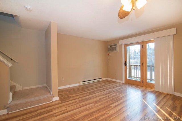 spare room with a wall mounted air conditioner, light hardwood / wood-style flooring, ceiling fan, and baseboard heating