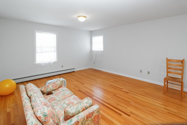 living area with wood-type flooring and baseboard heating