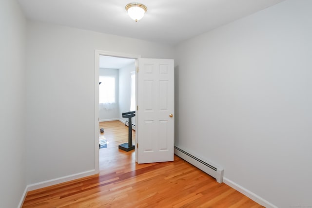 unfurnished room with baseboard heating and light wood-type flooring