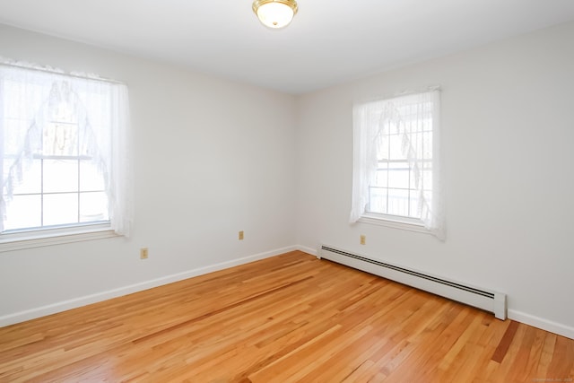 empty room featuring a baseboard radiator and light hardwood / wood-style floors