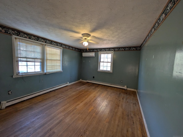 spare room with a wall unit AC, hardwood / wood-style floors, a textured ceiling, and a baseboard heating unit