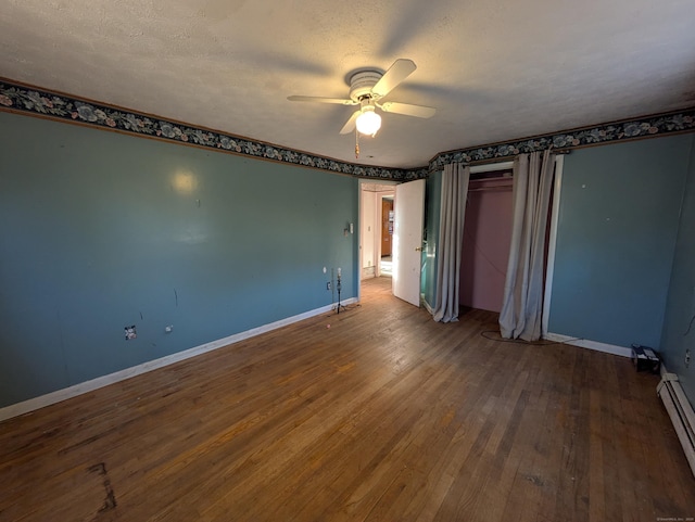 unfurnished bedroom featuring baseboard heating, ceiling fan, hardwood / wood-style floors, and a textured ceiling