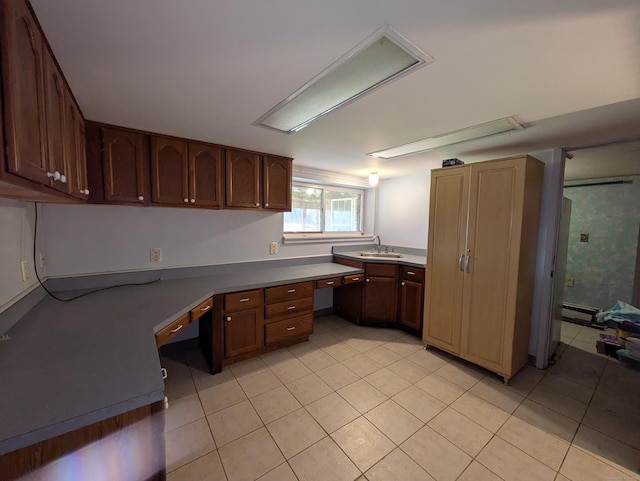 kitchen with sink, built in desk, baseboard heating, and light tile patterned flooring