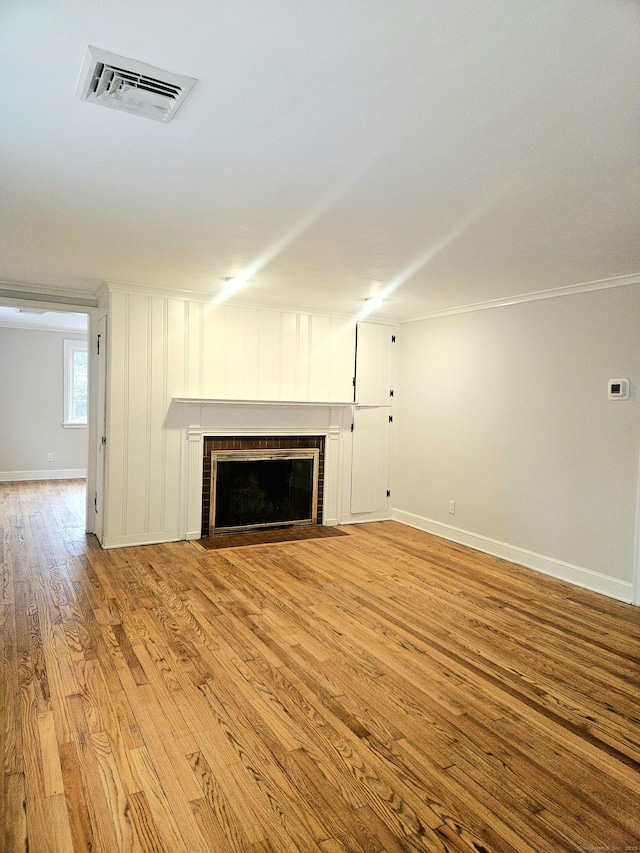 unfurnished living room with ornamental molding, a fireplace, and light hardwood / wood-style floors